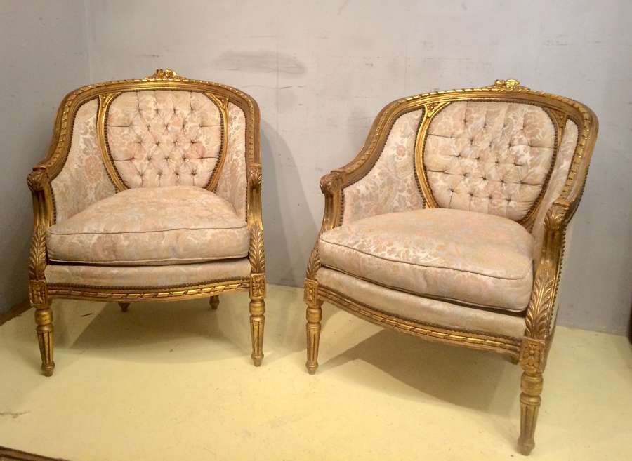 A pair of carved giltwood tub chairs in the French style.